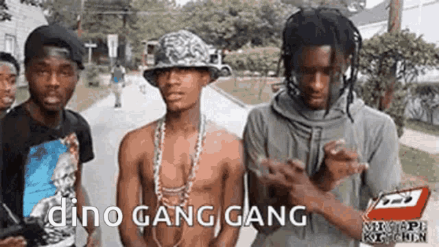 a group of young men are standing next to each other on a sidewalk and one of them is wearing a hat .