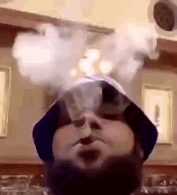 a man with a beard and a hat is smoking a cigarette .