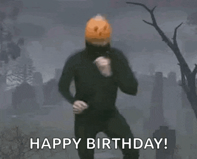 a man with a pumpkin on his head is dancing in a cemetery with the words `` happy birthday '' .