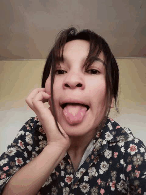 a woman sticking her tongue out and wearing a floral shirt