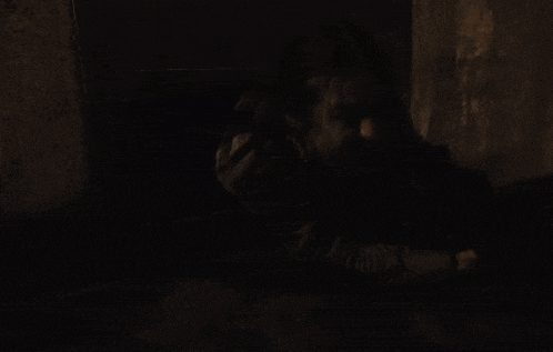a man is screaming in a dark room while standing in front of a wall .
