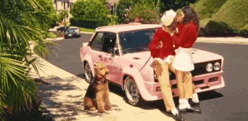a couple kissing next to a pink car