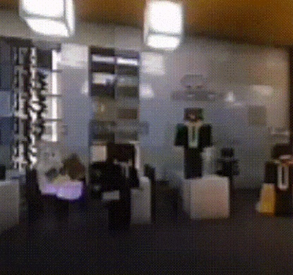 a blurred image of a room with a man in a green jacket