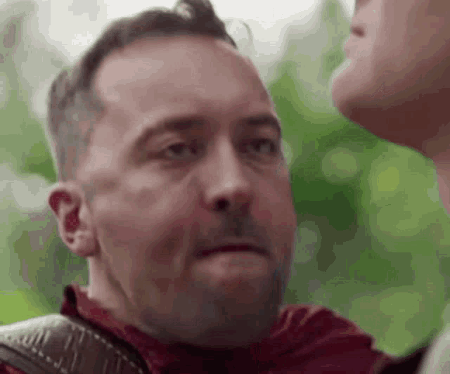 a man in a red shirt is talking to another man in a red shirt .