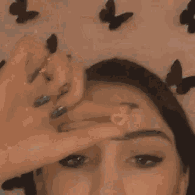 a woman with blue nails and a heart shaped ring on her finger is covering her face with her hand .