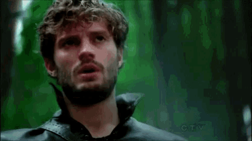 a man with a beard is wearing a black leather jacket and looking up into the sky .