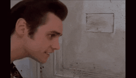 a man is looking through a hole in a wall at something .