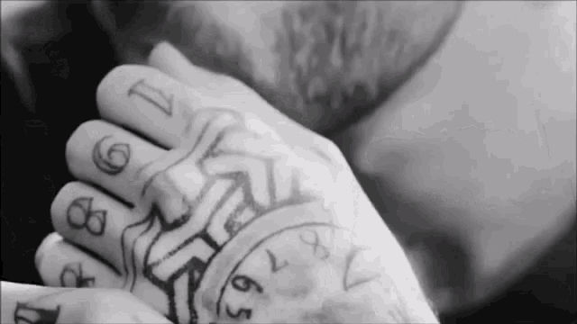 a black and white photo of a man 's hand with a tattoo of numbers on it