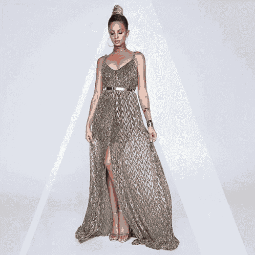 a woman wearing a long silver dress with a high slit