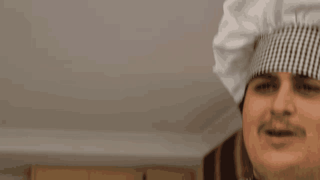a man wearing a chef 's hat with a black and white checkered pattern