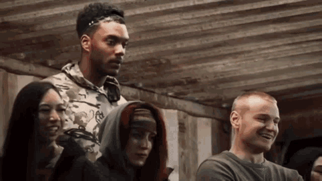 a group of people are standing in a room and one of them is wearing a hooded jacket