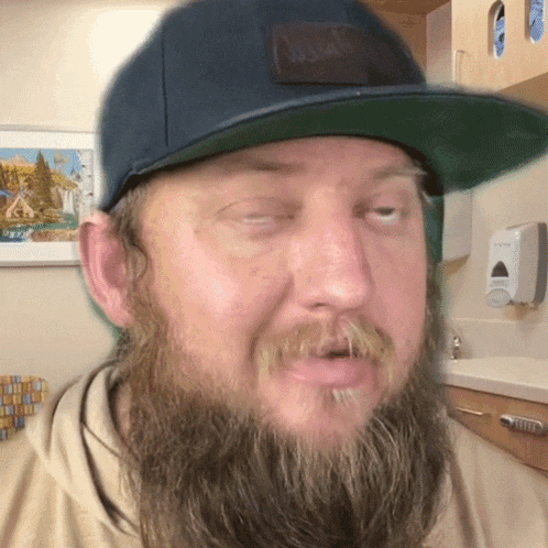 a man with a beard wearing a blue hat with the word columbia on the back