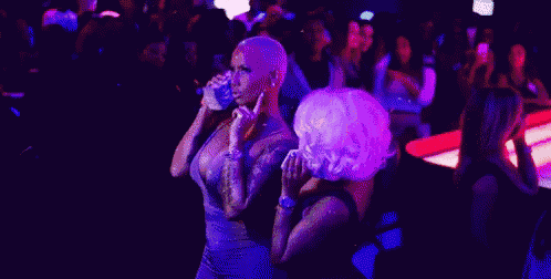 two women are holding stacks of money in their hands in a club .