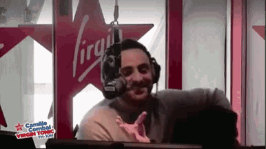 a man wearing headphones is in front of a virgin radio station