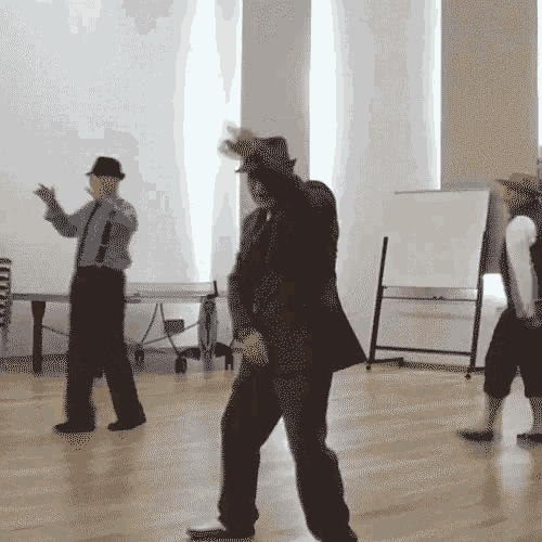 a man in a suit and hat is dancing in a room