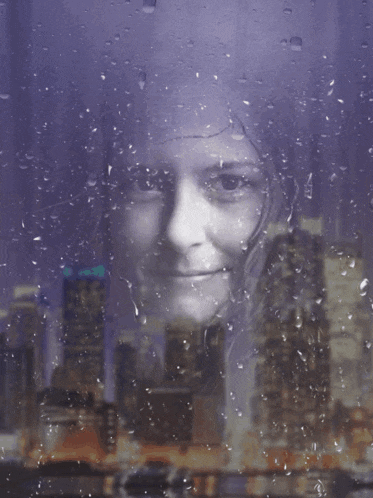 a woman 's face is behind a rainy window