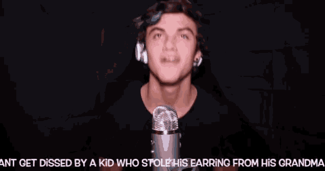 a young man wearing headphones is singing into a microphone while wearing earrings .