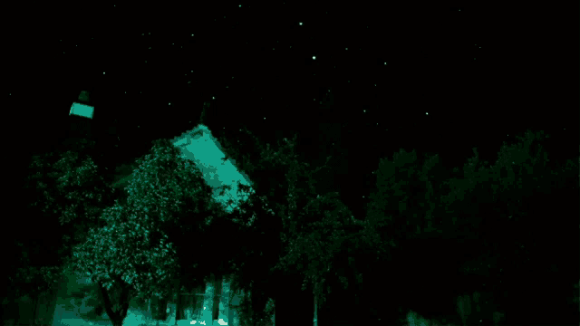 a house is lit up at night with trees in the foreground