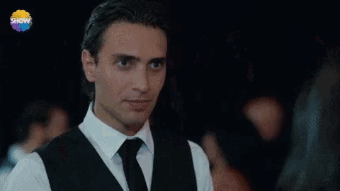 a man and two women are dancing in a room with tables and a sign that says show