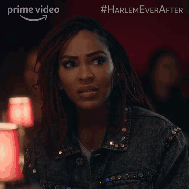 a woman with dreadlocks is wearing a black denim jacket with studs on it