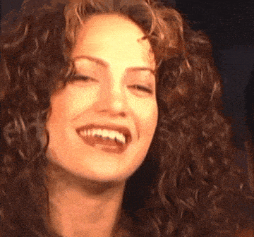 a close up of a woman with curly hair smiling
