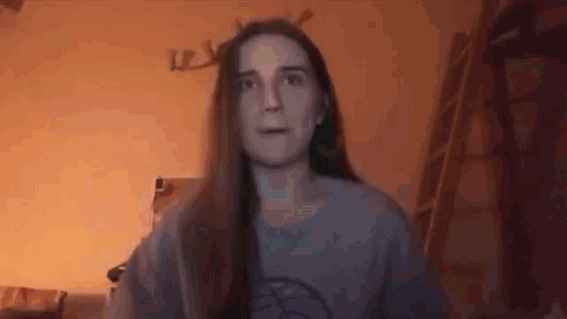 a woman with long hair is sitting in a room with a ladder .