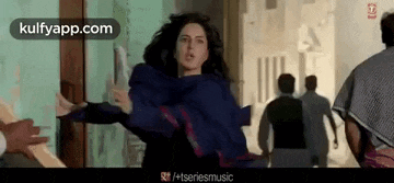 a woman in a blue dress is flying through the air while a group of people are walking behind her .