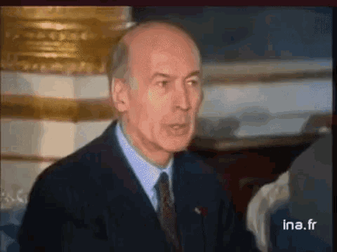 a man in a suit and tie is talking on a television screen with ina.fr written on the bottom of the screen