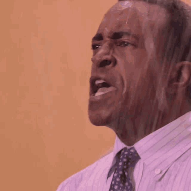 a man in a striped shirt and tie is sweating while making a funny face .