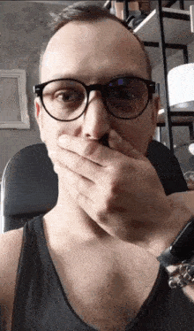 a man with glasses covering his mouth with his hand