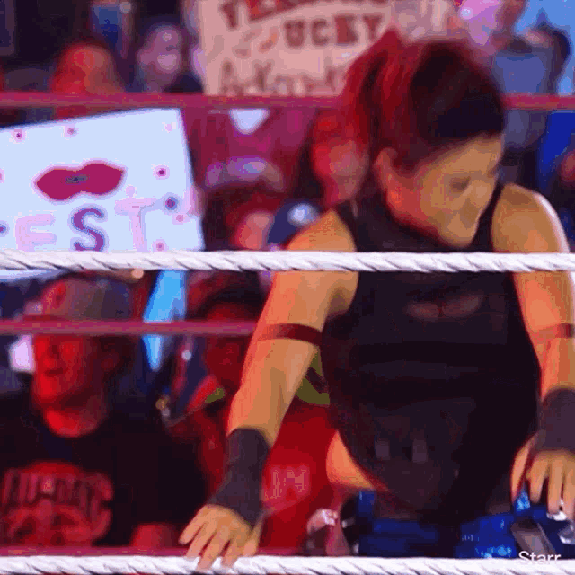 a woman is standing in a wrestling ring with a sign that says ucby in the background