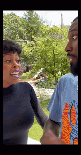 a man in a blue shirt with a butterfly on it talks to a woman in a black top