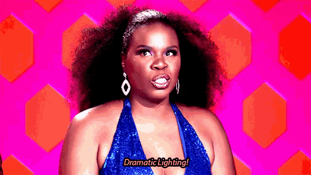 a woman in a blue dress and earrings is talking about dramatic lighting .