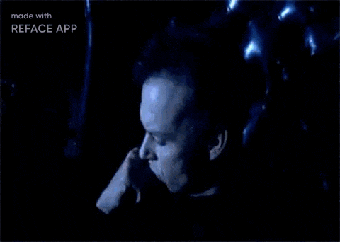 a man is sitting in a chair with his hand to his face .