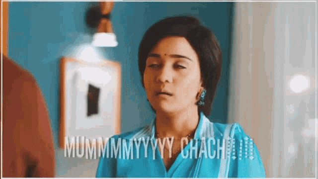 a woman in a blue dress is standing in a room with the words mummyyyy chach written on the bottom