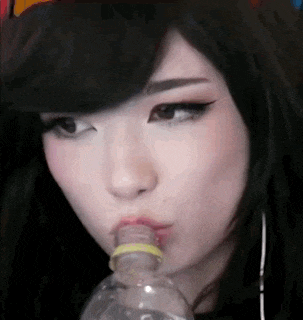 a woman is drinking water from a plastic bottle with a rubber band around her mouth .
