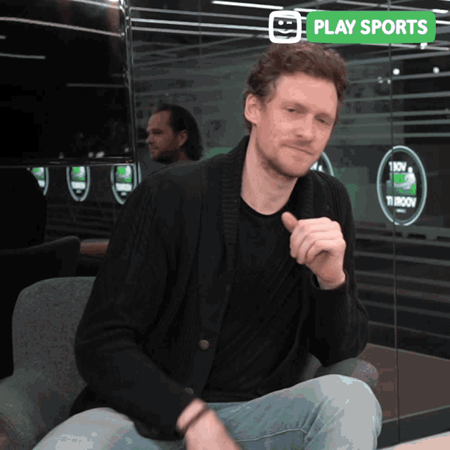 a man is sitting in front of a play sports advertisement
