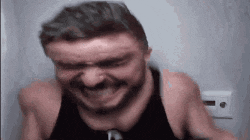 a man with a beard is making a funny face with his eyes closed .