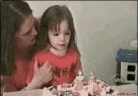a little girl is sitting at a table with a cake and candles .