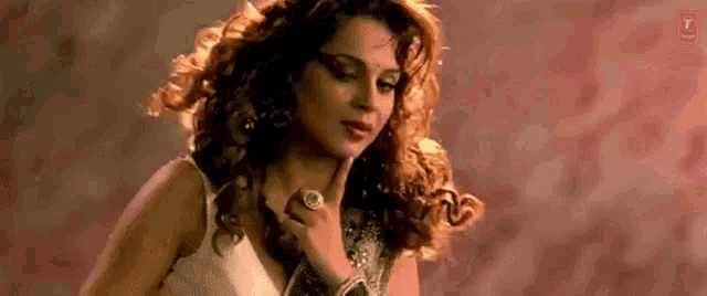 a woman with curly hair is wearing a ring on her finger .