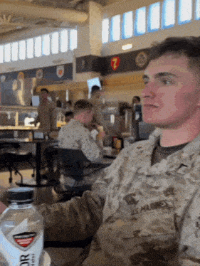 a man in a us marines uniform sits at a table in a restaurant