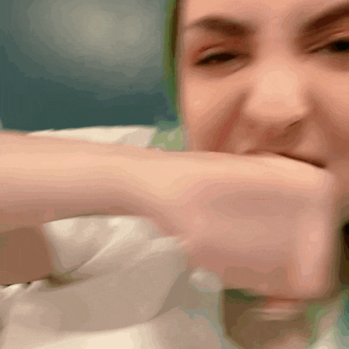 a woman covering her mouth with her fist in a blurry photo
