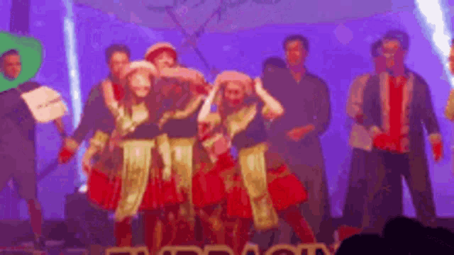 a group of people are dancing on a stage with the word city in the corner
