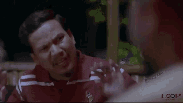 a man is making a funny face while talking to another man in a restaurant .