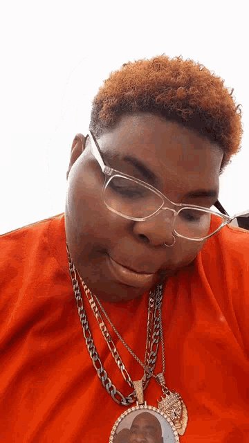 a man wearing glasses and a necklace has a picture of a man on it