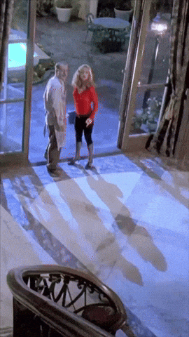 a man and a woman are standing in front of a large glass door