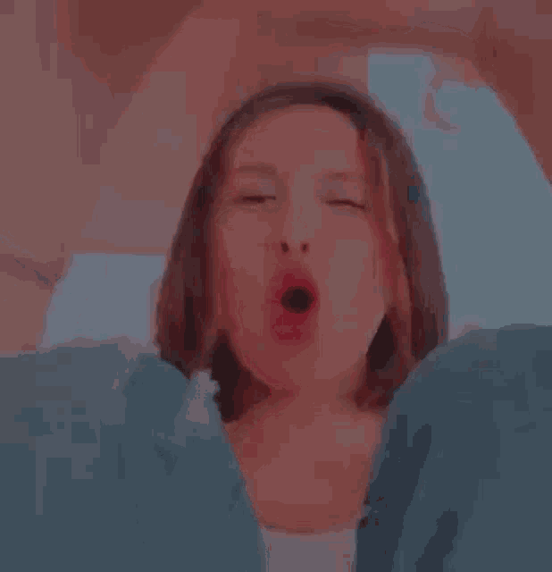 a close up of a woman making a funny face with her mouth open and her eyes closed .