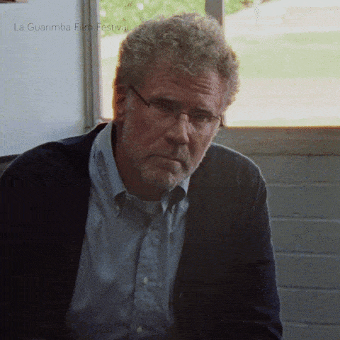 a man with glasses and a beard is sitting in front of a window with la guarimba film festival written on the bottom right