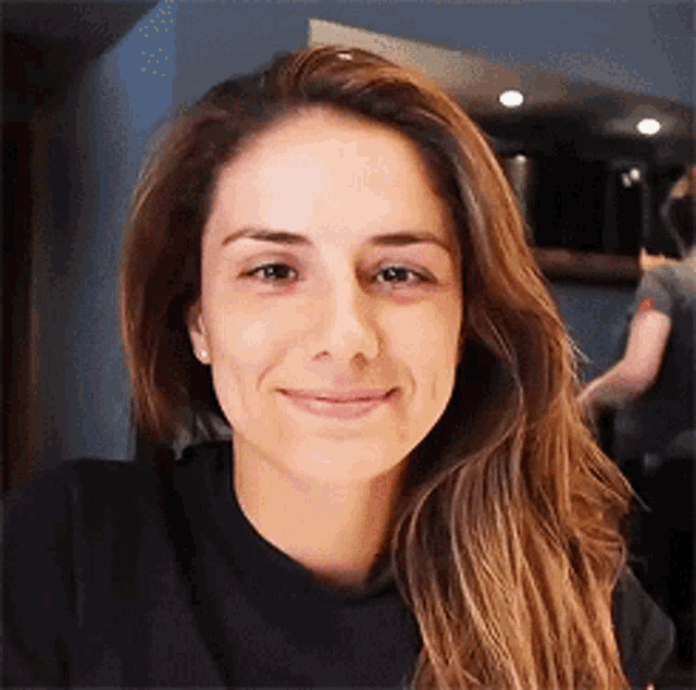 a woman with long brown hair is smiling for the camera