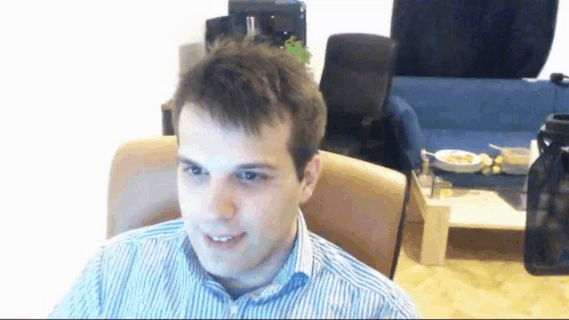 a man in a blue and white striped shirt is sitting in a chair